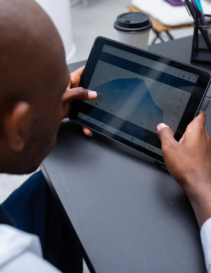 Man viewing graph on tablet at modern workspace, close up.